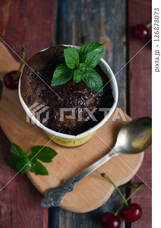 Chocolate cake with fresh mint served in rustic coffee cup on vintage wooden background perfect for bakery advertisements dessert menus and rustic food styling concepts 126878073