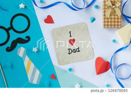 I love dad message on white card paper tie mustache shirt glasses red hearts gift box blue ribbon layout flat lay photo Fathers Day greeting background handmade composition 126878085