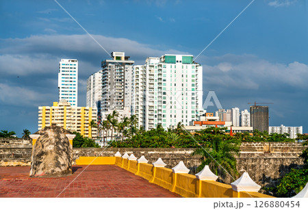 Modern high-rise buildings of Cartagena, Colombia rise beyond the historic yellow fortification walls under a dramatic sky Modern high-rise buildings of Cartagena, Colombia rise beyond the historic yellow fortification walls under a dramatic sky 126880454