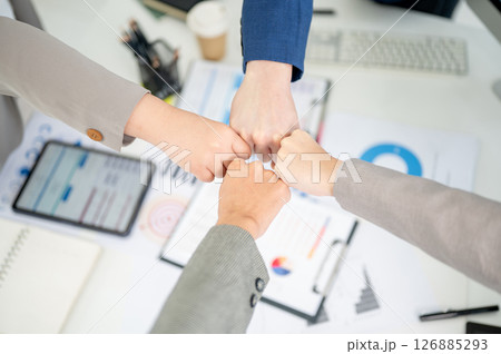 Top view of businessman and woman or office workers bumping fists over table with scattered document Top view of businessman and woman or office workers bumping fists over table with scattered document 126885293