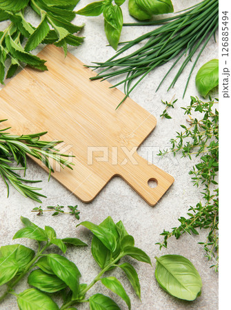 Fresh herbs and empty cutting board lying on kitchen table Fresh herbs and empty cutting board lying on kitchen table 126885494