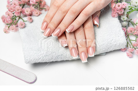 Woman showing her french manicure on a white towel 126885502