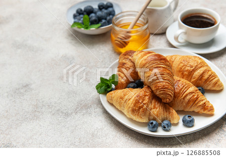 Delicious french croissants with coffee, honey, and fresh blueberries for breakfast 126885508