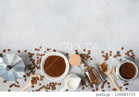 Coffee preparation scene featuring ground coffee, beans, milk, and tools arranged on a textured surface, creating an inviting atmosphere for enthusiasts Coffee preparation scene featuring ground coffee, beans, milk, and tools arranged on a textured surface, creating an inviting atmosphere for enthusiasts 126885715