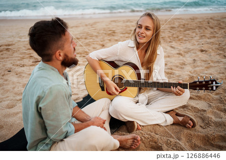 A Couple Enjoying Beautiful Music Together on the Beach During a Stunning Sunset A Couple Enjoying Beautiful Music Together on the Beach During a Stunning Sunset 126886446
