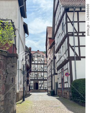 Cobbled street flanked by traditional half-timbered houses in a quaint medieval town. The narrow alley captures the charm of historical European architecture on a sunny day, Germany 126886600