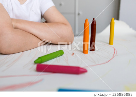 Child coloring with colorful crayons at a table 126886885