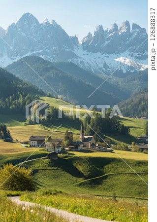 Visit Italy. Morning light spills over Santa Maddalena quaint village and sharp Dolomite peaks, a vertical frame of alpine calm and storybook charm Visit Italy. Morning light spills over Santa Maddalena quaint village and sharp Dolomite peaks, a vertical frame of alpine calm and storybook charm 126888317