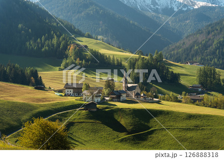 Visit Italy. Santa Maddalena wakes in soft golden light, church spire rising beneath the jagged Dolomites, a peaceful morning in the heart of South Visit Italy. Santa Maddalena wakes in soft golden light, church spire rising beneath the jagged Dolomites, a peaceful morning in the heart of South 126888318