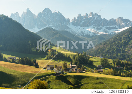 Visit Italy. Framed by towering peaks, the quiet village of Santa Maddalena glows at sunrise, a serene start to the day in the dramatic Dolomites 126888319