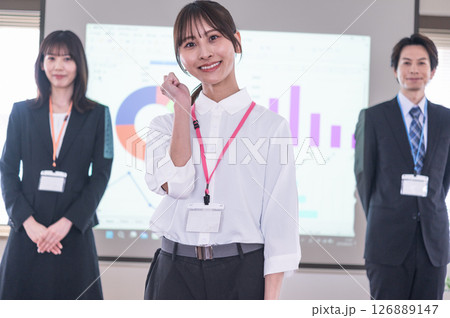 会議室のスクリーンの前でポーズする若い女性 126889147