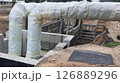 Insulated pipes emerging from underground concrete structure 126889296