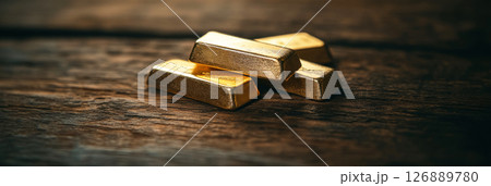 Gold bars sit on dark wood with matte depth and subtle light, captured in still product style for premium and elegant finance settings, banner 126889780