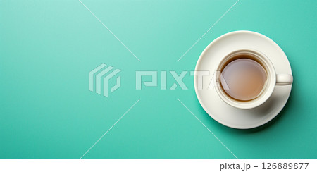 A top view of a white tea cup rests on a vibrant green backdrop, providing ample space for text and creating a fresh, inviting atmosphere 126889877