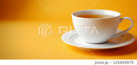 Close-up of white tea cup on a vibrant yellow background with empty space 126889878