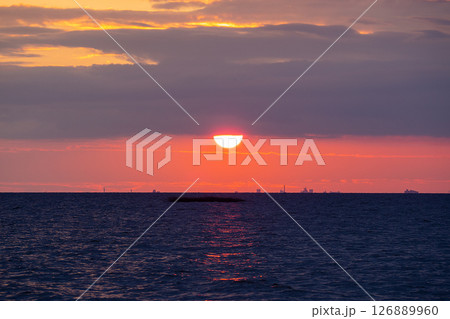 Scenic sunset over the sea. The sun is peeking out from behind the clouds. 126889960