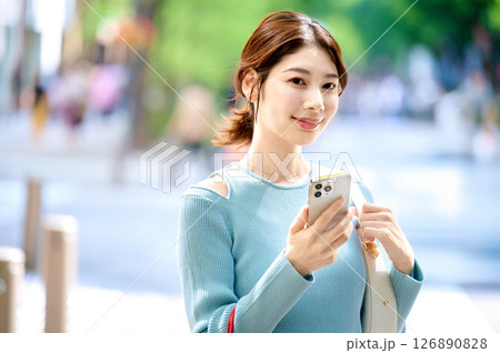 ショッピングしながらスマホを操作するオシャレな若い女性 126890828