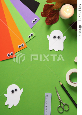 Handmade paper ghosts with googly eyes on green background. Desktop for paper crafts. Top view, space for text. Handmade paper ghosts with googly eyes on green background. Desktop for paper crafts. Top view, space for text. 126891185