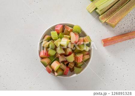 Freshly chopped green rhubarb in white bowl on white background. Trendy organic food. Ready for cooking. Vegan concept. View from above. Freshly chopped green rhubarb in white bowl on white background. Trendy organic food. Ready for cooking. Vegan concept. View from above. 126891328