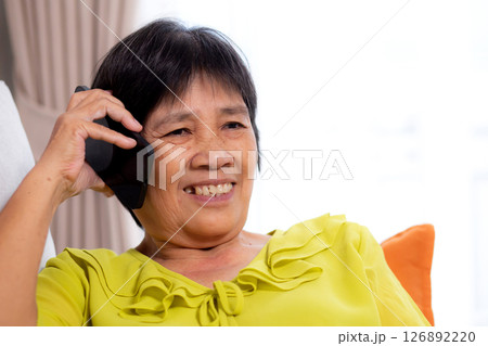 Senior asian woman telephone smiling and relax sitting on sofa in living room at home. Senior asian woman telephone smiling and relax sitting on sofa in living room at home. 126892220