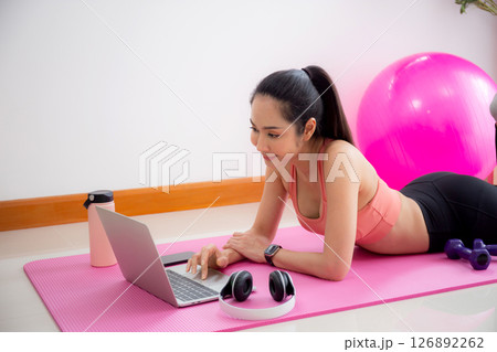 Young asian woman video call with friends after practice yoga and workout for relax in living room. Young asian woman video call with friends after practice yoga and workout for relax in living room. 126892262