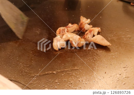 close up of pan frying squid cut into pieces in Japanese teppanyaki  126893726