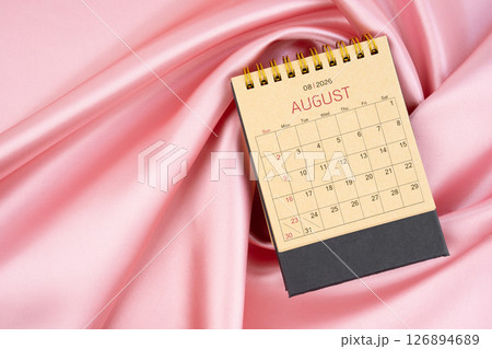 August 2026 craft brown paper desk calendar on pink silk textile background. August 2026 craft brown paper desk calendar on pink silk textile background. 126894689