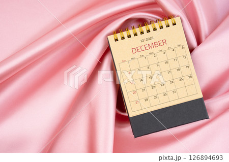 December 2026 craft brown paper desk calendar on pink silk textile background. 126894693