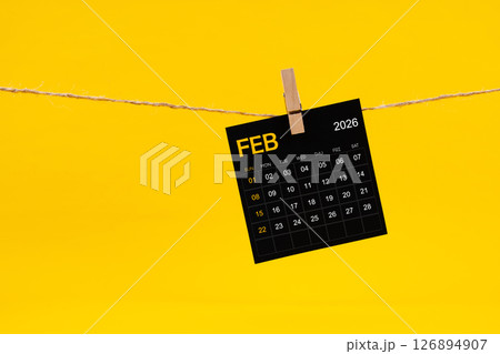 February 2026 black calendar hanged with brown rope on yellow background. 126894907
