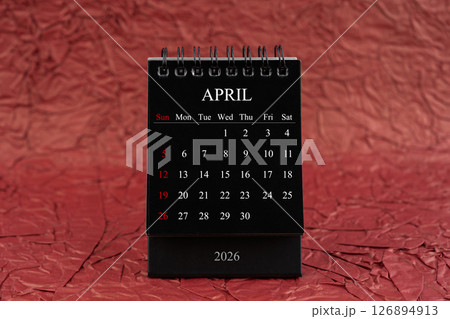 April 2026, Front view black desk calendar on crumpled red paper. April 2026, Front view black desk calendar on crumpled red paper. 126894913