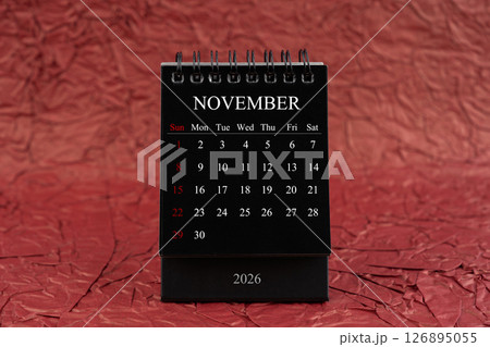 November 2026, Front view black desk calendar on crumpled red paper. November 2026, Front view black desk calendar on crumpled red paper. 126895055