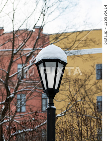 A street lamp topped with snow stands in a winter setting 126895614