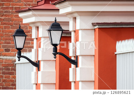 Classic black street lamps against a vivid red masonry background 126895621