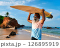 Senior man with surfboard walks on sandy beach. Elderly surfer embraces active lifestyle. Mature male enjoys ocean waves. Silver-haired sportsman finds joy in surfing. Healthy aging, vibrant life. 126895919