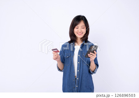 Southeast asian woman smiling while using internet for online shopping holding credit card and smartphone against white background 126896503