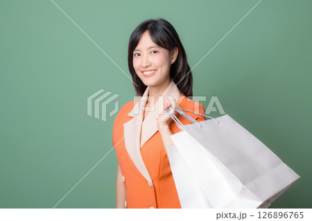 Southeast asian woman smiling while holding shopping bags showing happiness with internet online shopping against green background Southeast asian woman smiling while holding shopping bags showing happiness with internet online shopping against green background 126896765