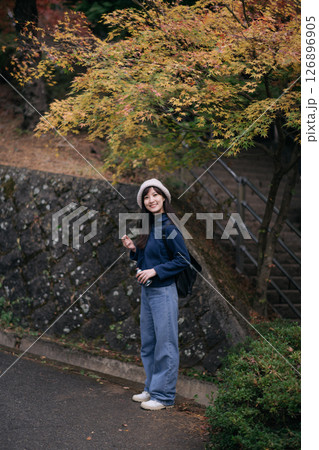 Southeast Asian woman travel in autumn park wearing casual clothes and hat smiling happily near colorful tree with backpack enjoying outdoor nature Southeast Asian woman travel in autumn park wearing casual clothes and hat smiling happily near colorful tree with backpack enjoying outdoor nature 126896905