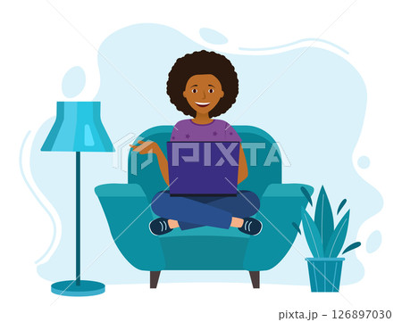 a girl is sitting at a laptop. in the chair. The lamp is on the floor 126897030