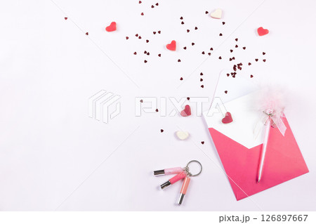 Invitation card to romantic party, wedding or anniversary. Red paper envelope, confetti and sweets in form hearts on light background. Top view, flat lay, copy space Invitation card to romantic party, wedding or anniversary. Red paper envelope, confetti and sweets in form hearts on light background. Top view, flat lay, copy space 126897667