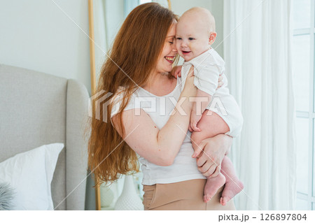 Happy family at home. Mother holding little toddler child daughter. Mom and baby girl relax playing having fun together at home. Mother hugs baby with love care. Mom of breast feeding baby Happy family at home. Mother holding little toddler child daughter. Mom and baby girl relax playing having fun together at home. Mother hugs baby with love care. Mom of breast feeding baby 126897804