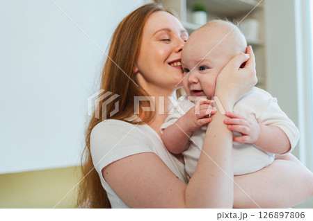 Happy family at home. Mother holding little toddler child daughter. Mom and baby girl relax playing having fun together at home. Mother hugs baby with love care. Mom of breast feeding baby Happy family at home. Mother holding little toddler child daughter. Mom and baby girl relax playing having fun together at home. Mother hugs baby with love care. Mom of breast feeding baby 126897806