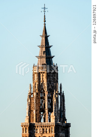 A majestic view of the Toledo Cathedral's intricate bell tower piercing the clear, blue Spanish sky. 126897921