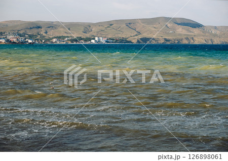 Koktebel bay showing signs of blooming algae with distant city and bare mountains in Crimea Koktebel bay showing signs of blooming algae with distant city and bare mountains in Crimea 126898061