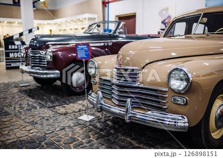 Beige Pobeda car showing in front of a vintage maroon car in a museum Beige Pobeda car showing in front of a vintage maroon car in a museum 126898151