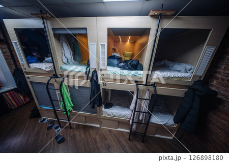 Capsule hotel beds showing clothes and bags hanging, offering affordable accommodation 126898180
