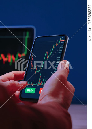Close up, trader hands holding smartphone with trading application 126898226