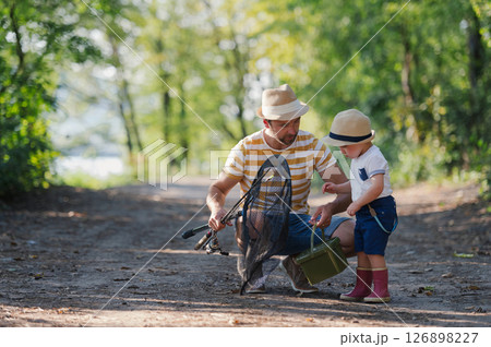 Father and little son walking together in nature on a fishing trip 126898227