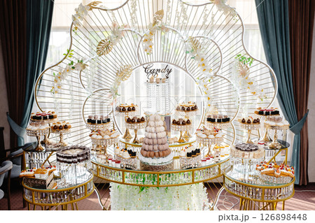 Delicious macarons and pastries decorating a luxurious candy bar buffet Delicious macarons and pastries decorating a luxurious candy bar buffet 126898448