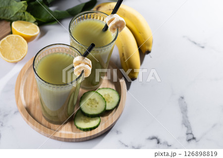 Green smoothie with spinach,banana, apple, and lemon on white marble Green smoothie with spinach,banana, apple, and lemon on white marble 126898819