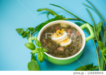 Homemade green borscht with boiled egg and fresh sorrel on top on a blue background Homemade green borscht with boiled egg and fresh sorrel on top on a blue background 126898959